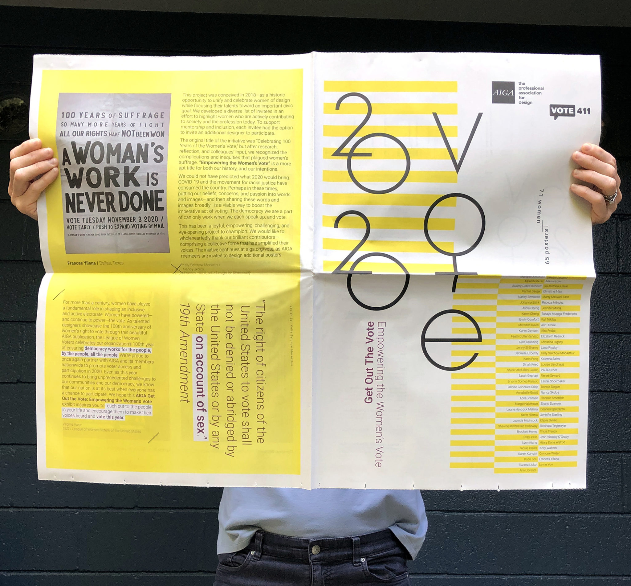 Kelly Salchow MacArthur's hands holding a designed poster covering her face, mostly yellow and grey.