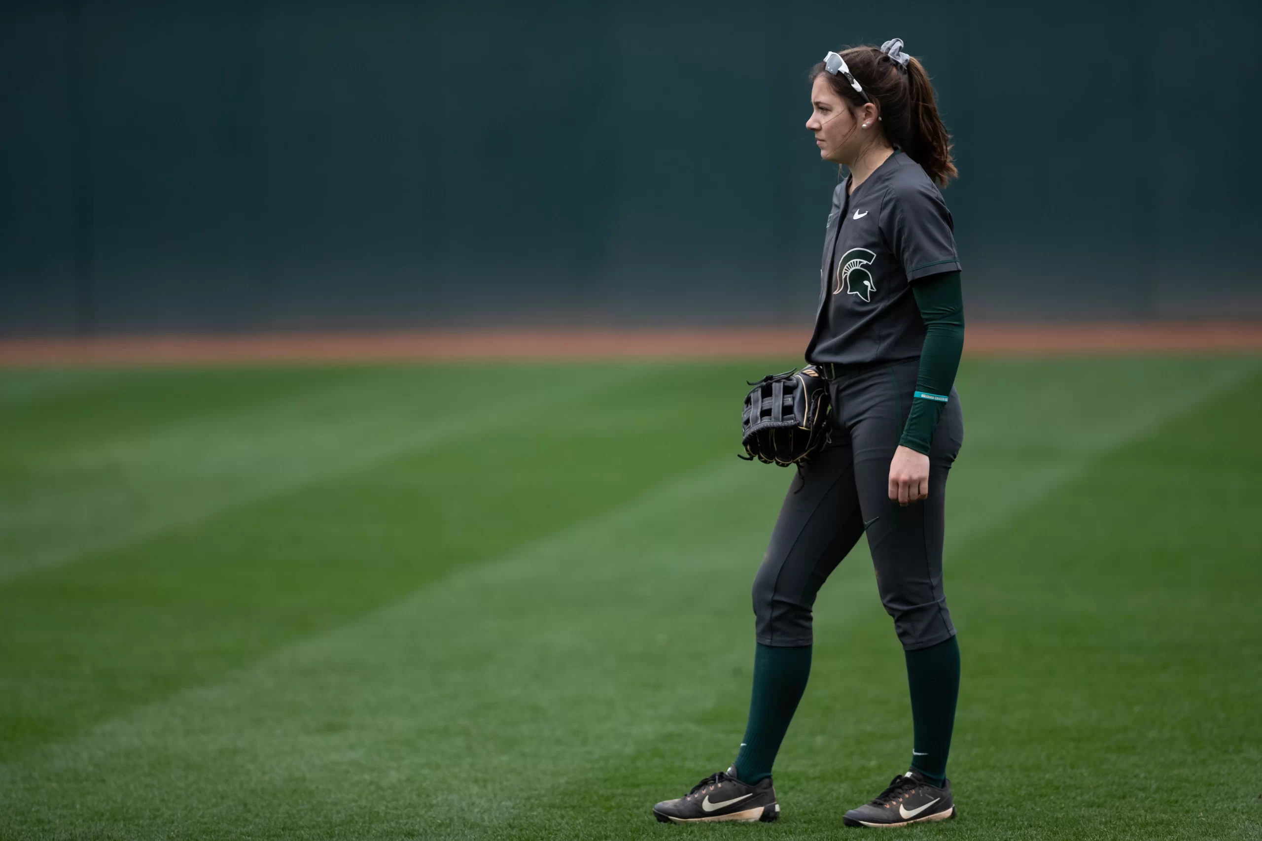 Katie Quinlan standing on green softball field at MSU.