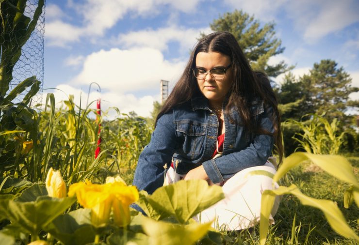 Mikayla in jean jacket leaning forward looking at yellow flowers