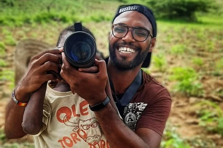 Vadu helping a child hold a camera.