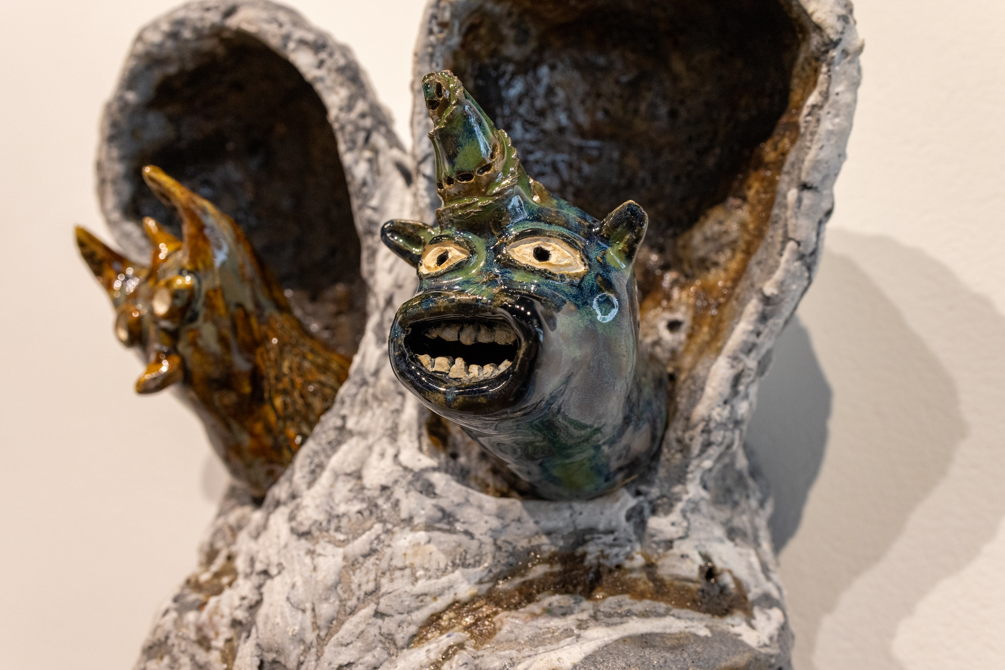 A close up of two ceramic figures that appear to be poking their heads out of two ears.