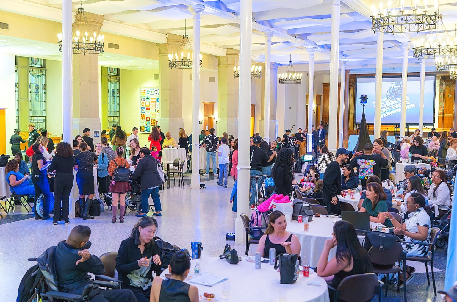 Audience members and participants gather inside a large, brightly lit hall during the 2025