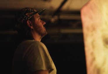 Man in baseball hat looks at glowing yellow screen