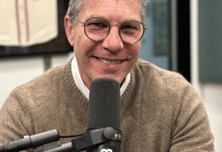 MSU Museum Director Devon Akmon sits in front of a microphone smiling.