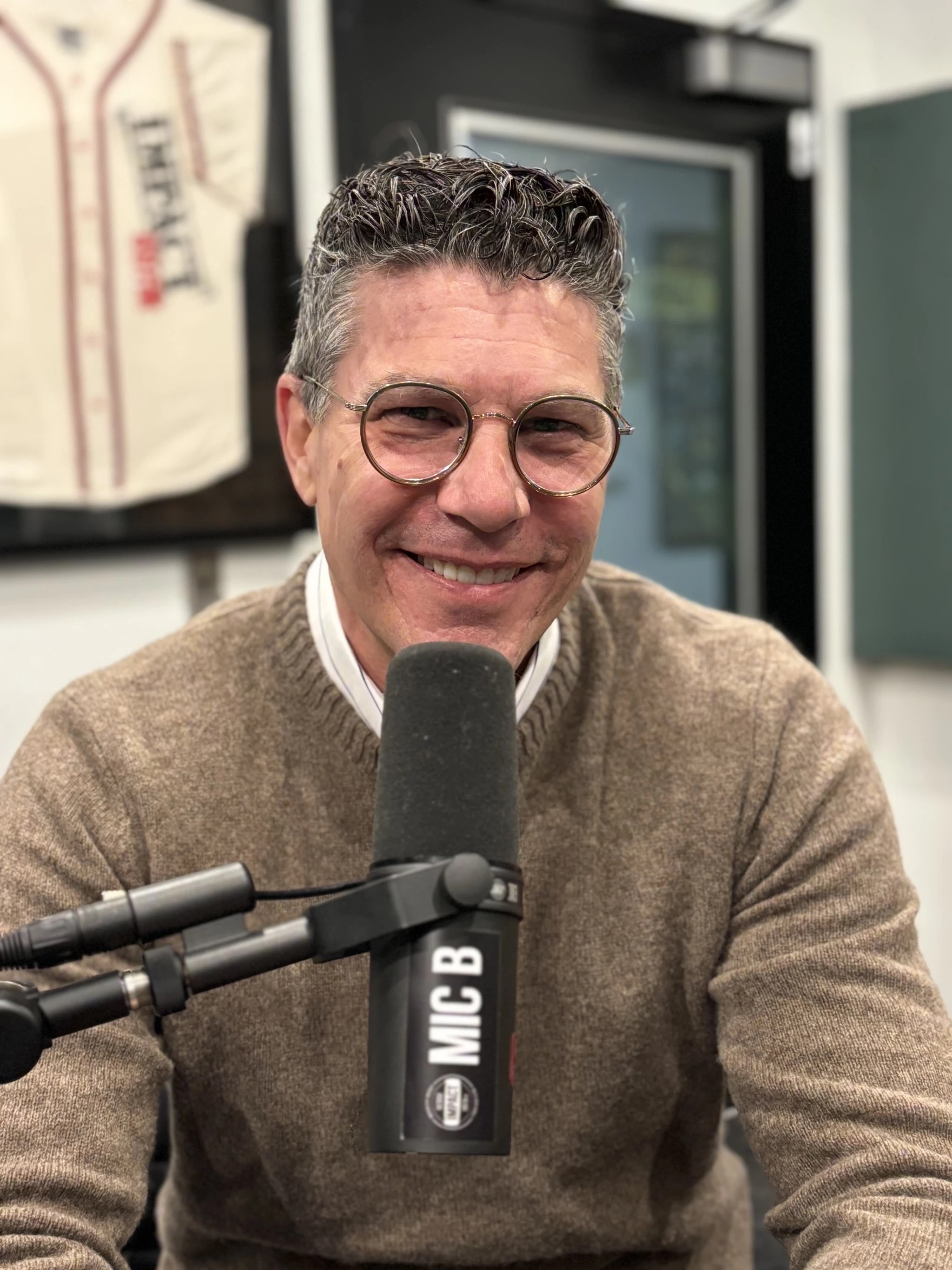MSU Museum Director Devon Akmon sits in front of a microphone smiling.