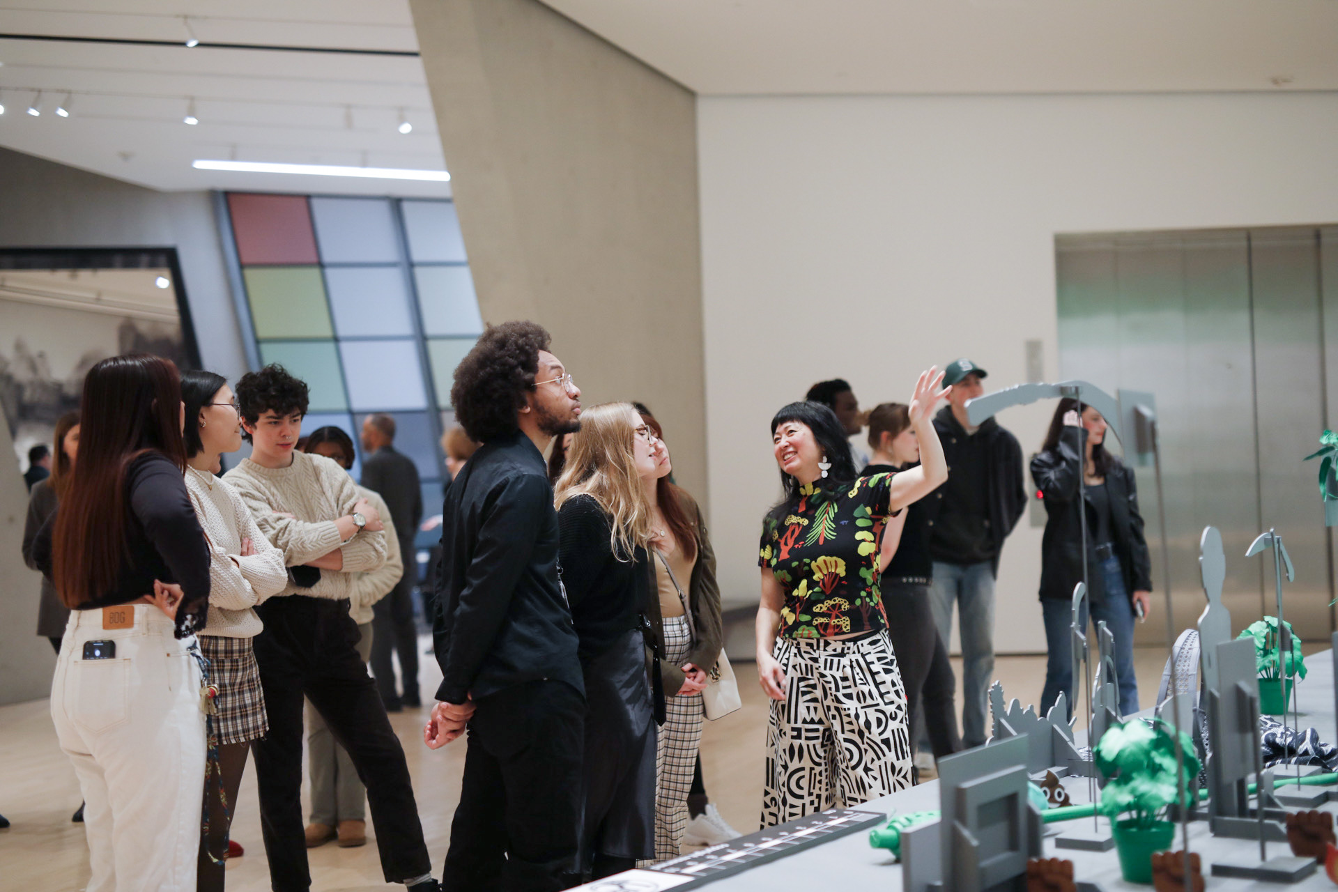 Students look up as artist points to work and smiles