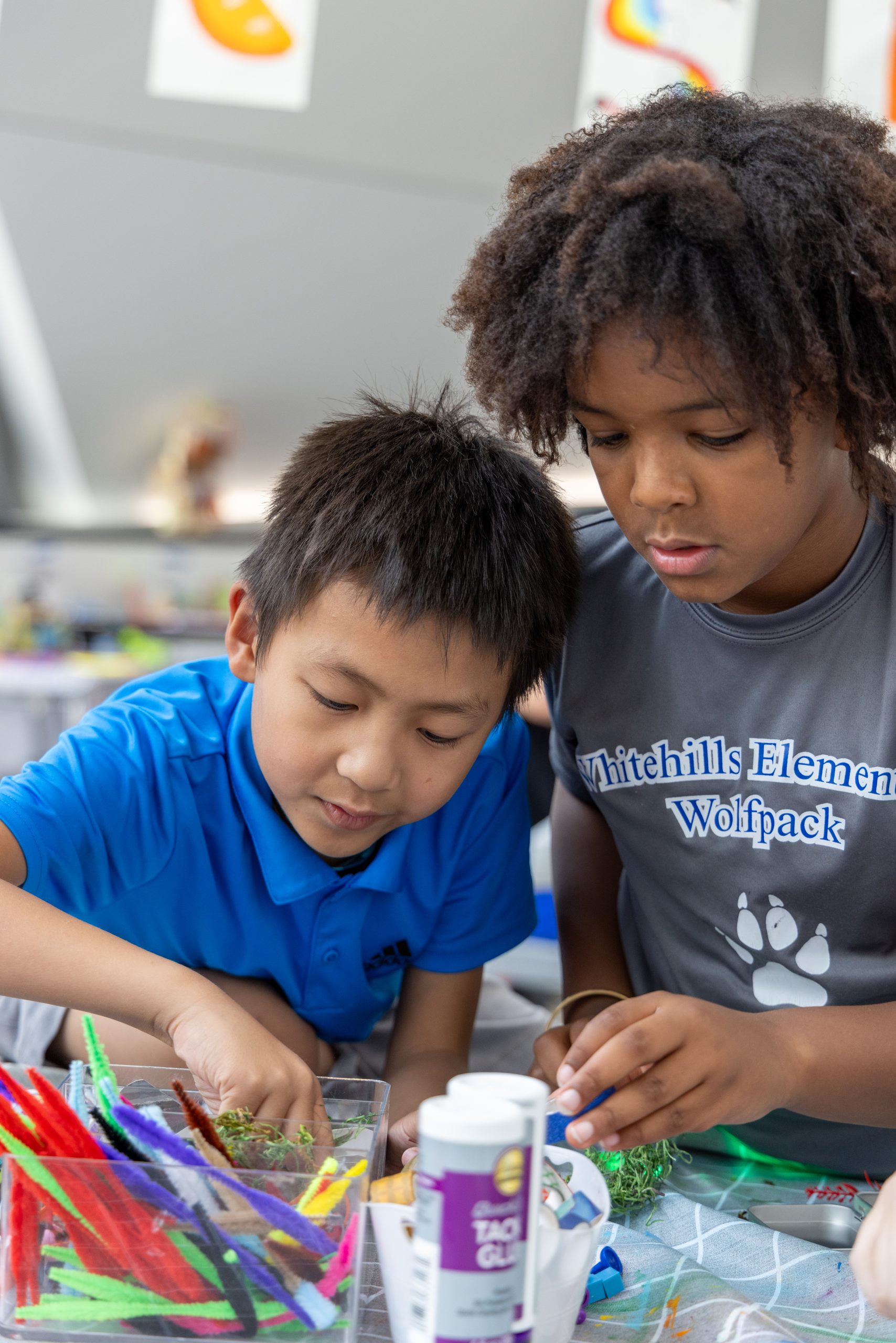 Two boys work with craft supplies on a table