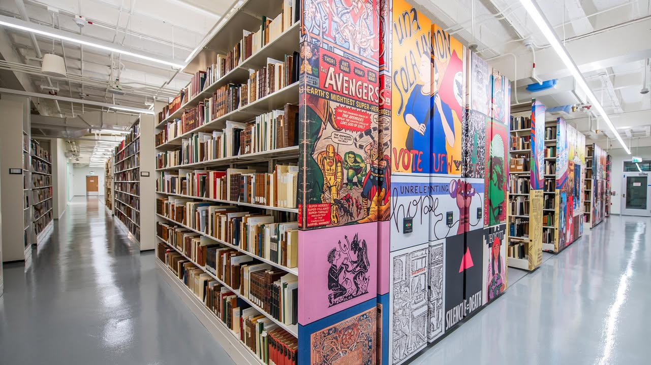 Shelves and shelves of books, with the side of the shelves covered with a collage of images from the collection