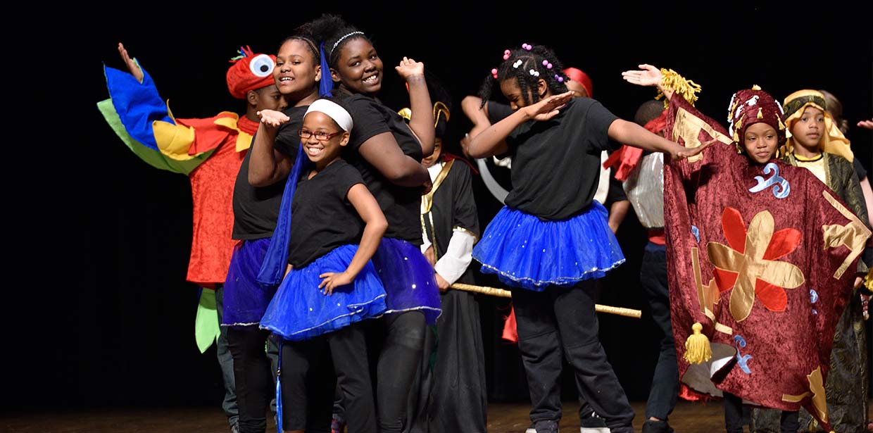 Kids smile and dance on stage in costume