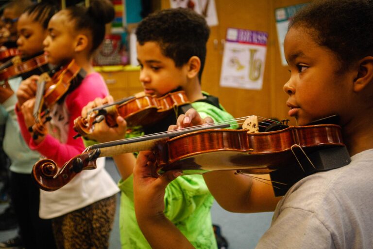 Four childen learn to play violin