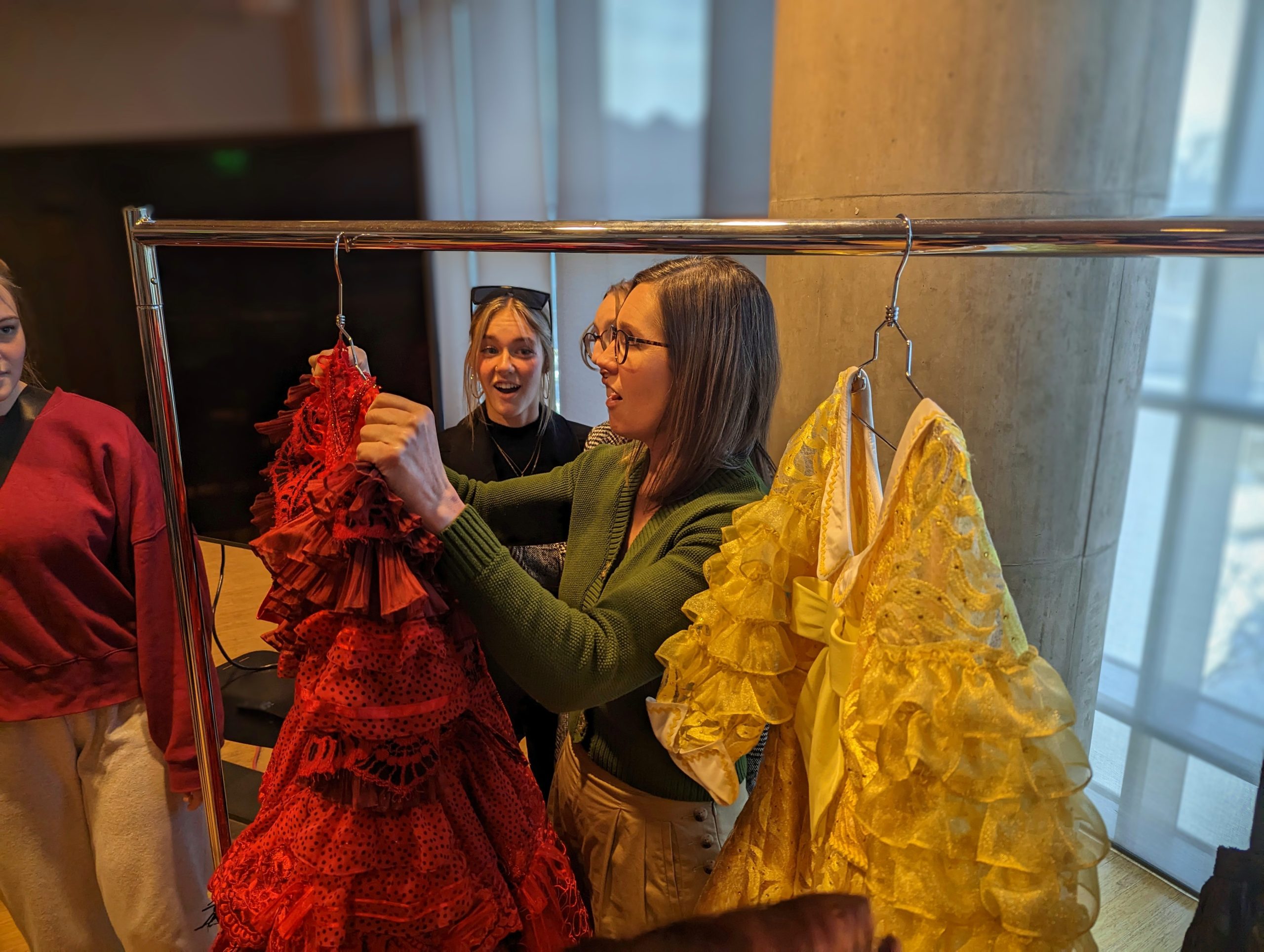 An MSU student looks at a costume, a red frilly dress, in awe