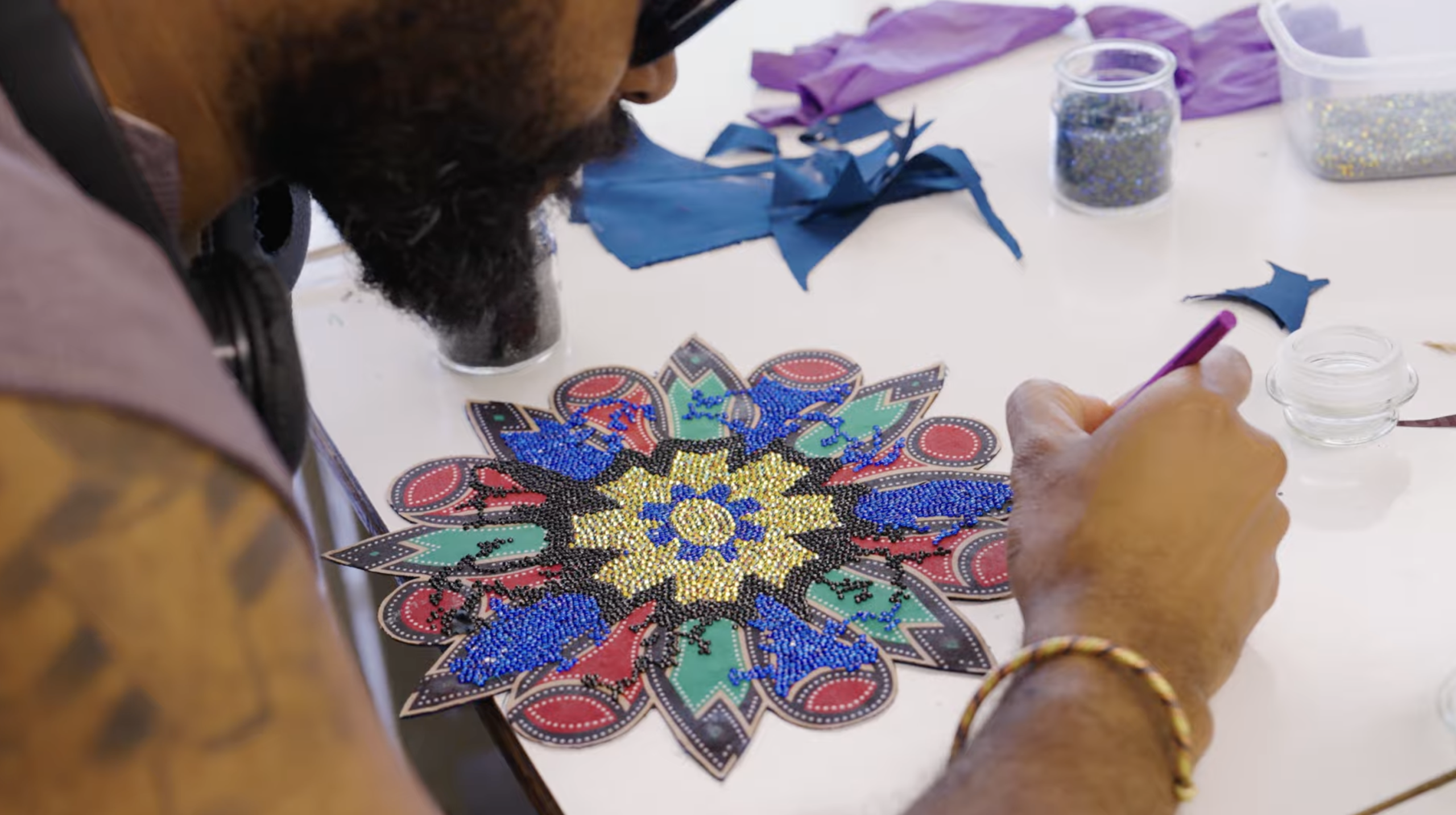 Man with beard beads a cut paper mandala