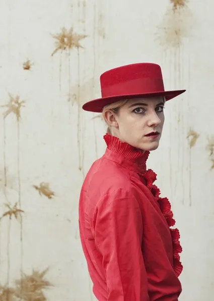 Image of woman with blonde hair in red shirt and hat looking at camera