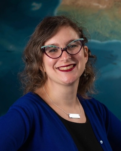 Portrait of Shannon Schmoll wearing cat-eye glasses and smiling.