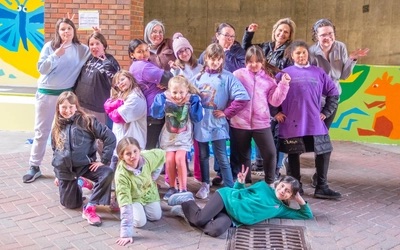 Girl Scouts Troop 30418 pose as a group in front of a mural.