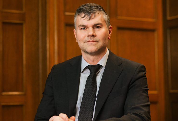 Thomas Stubblefield, Dean of Michigan State University College of Arts and Letters, sits in a wood paneled room. He is wearing a black blazer and tie.