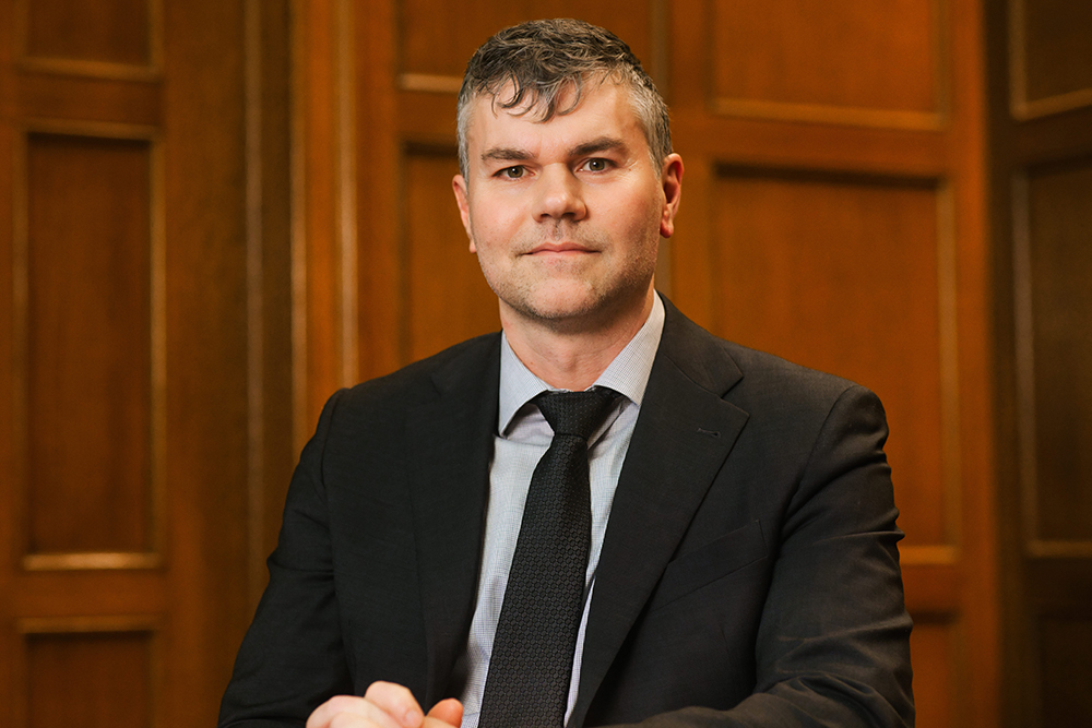 Thomas Stubblefield, Dean of Michigan State University College of Arts and Letters, sits in a wood paneled room. He is wearing a black blazer and tie.