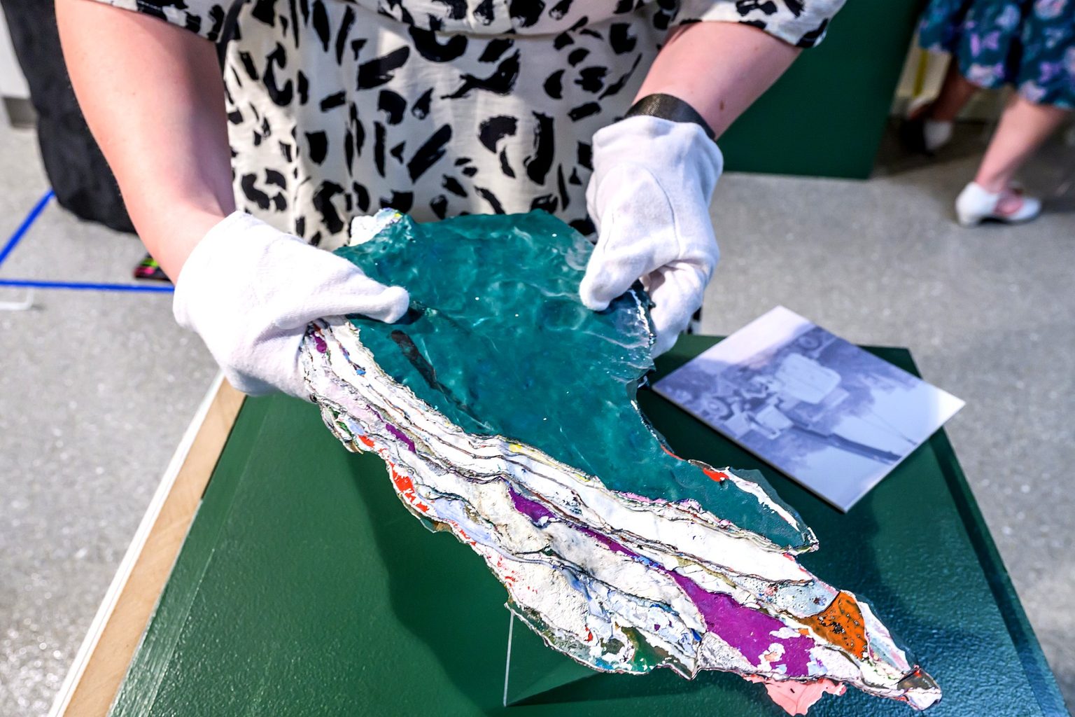 A person wearing white gloves holds a segment of the MSU Rock, revealing the layers of paint.
