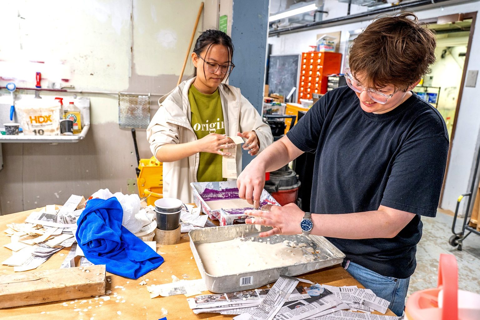 Two students mix paper pulp and recycled newspaper materials for the paper mache replica of the MSU Rock.