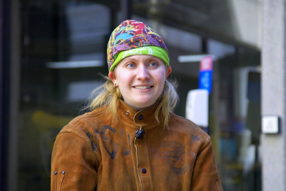 A faculty member wearing colorful bandanas and a leather safety jacket used in metal casting.