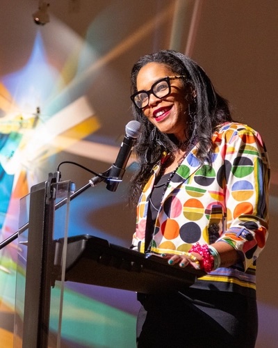 Dr. Ruth Nicole Brown speaks at a podium at the exhibit opening at the Flint Institute of Arts.