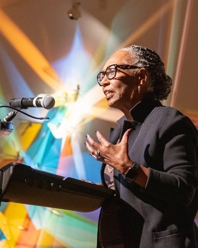 Dr. Gwendolyn Taylor stands at a podium talking to an audience at Flint Institute of Arts.