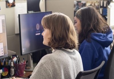 Two students working on computers at a desktop.