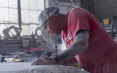 Sculptor Jason Qugino works on a stone carving inside his studio.